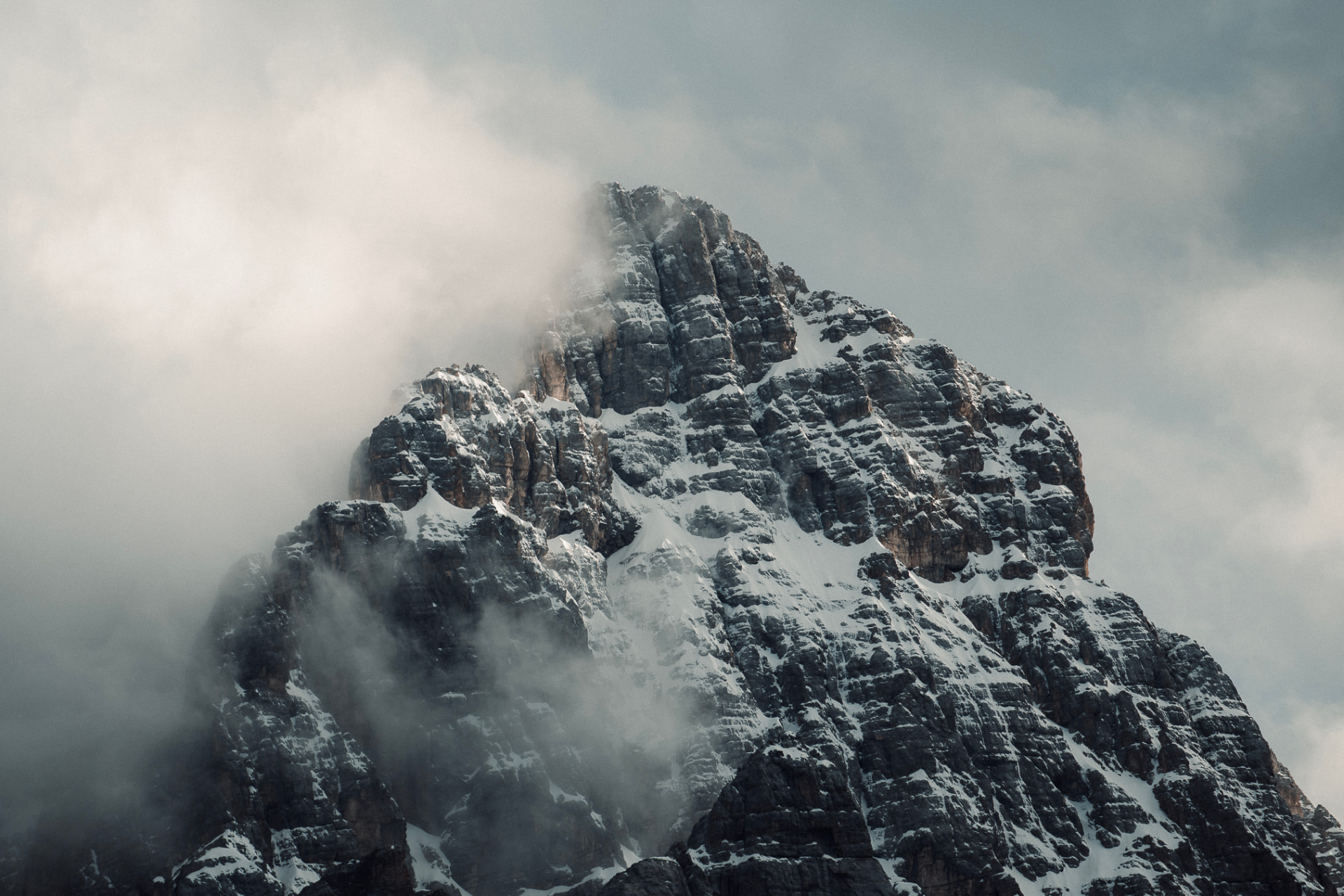 Snow-covered rock peak wrapped in clouds