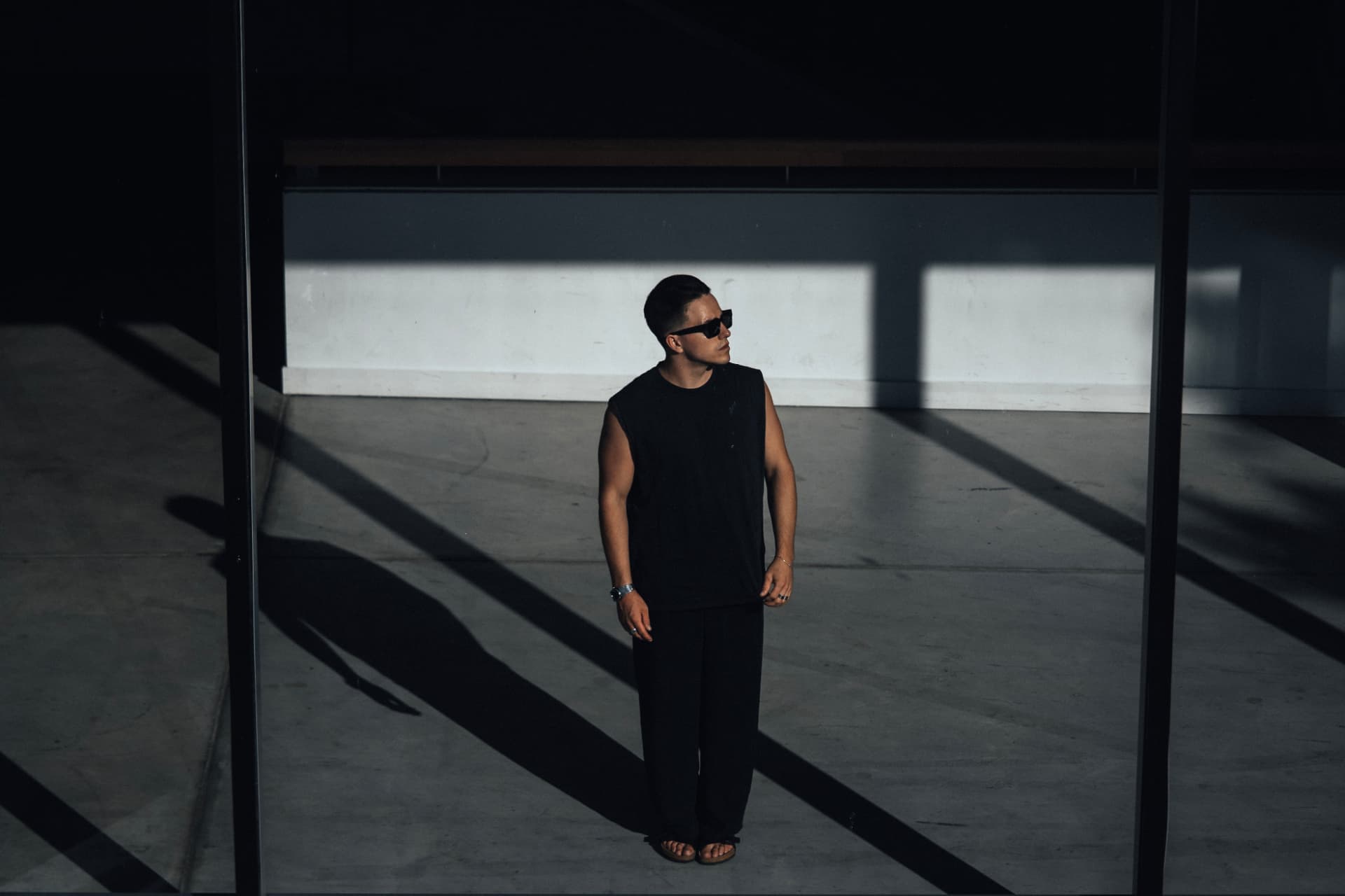 Figure in black standing in hard sunlight and long shadows